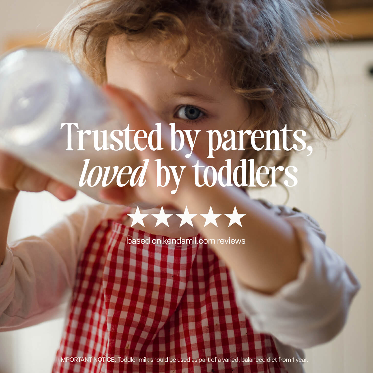A young child with curly hair, wearing a red and white checkered apron, drinks from a bottle. Text on the image reads: Trusted by parents, loved by toddlers—our 6x200ml Organic Ready to Feed Toddler Milk is enriched with vitamins and has a five-star rating.