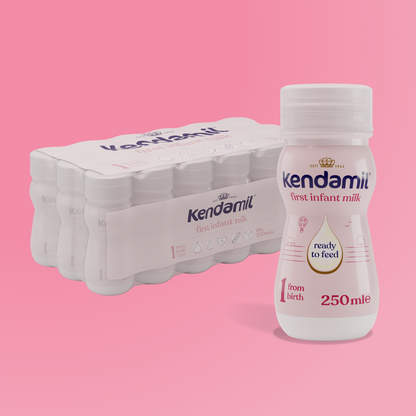 A bottle of 18x250ml Classic Ready to Feed infant milk, made from grass-fed cows and whole milk formula, stands in front of a six-pack. The label reads “ready to feed, from birth” on a pink background.