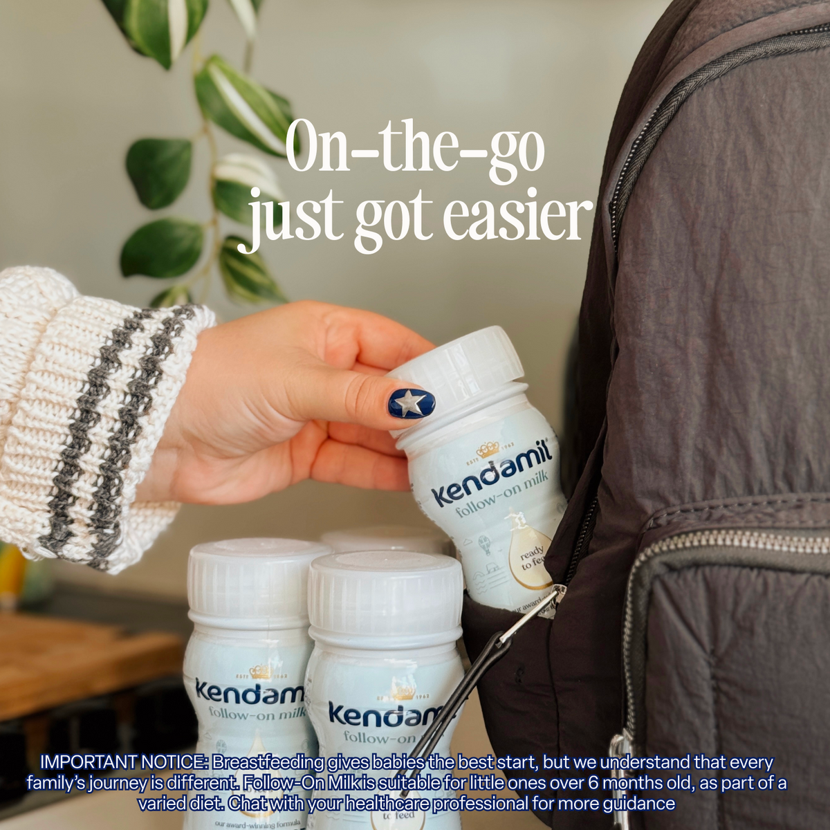 A hand places a bottle of Kendamil 18x250ml Classic Follow-On Ready to Feed formula, made with plant-based DHA, into the zippered pocket of a gray backpack. Two more bottles are visible nearby, with the text “On-the-go just got easier” above them.